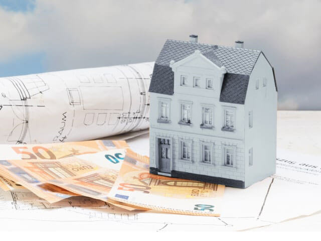Verkehrswertermittlung (© adobe Stock 1017858682 von Maren Winter) Verkehrswertermittlung Modellhaus mit Bauzeichnung und Geldscheinen
